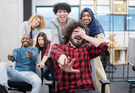 Multiethnics startup business team of software developers having fun while racing on office chairs,excited diverse employees laughing enjoying funny activity at work breakの写真素材