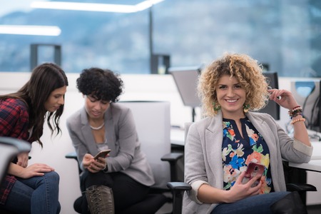 Portrait of successful female software developer with a curly hairstyle at modern busy startup officeの写真素材