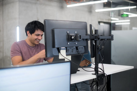 Young multiethnics business team of software developers working together using laptop and desktop...