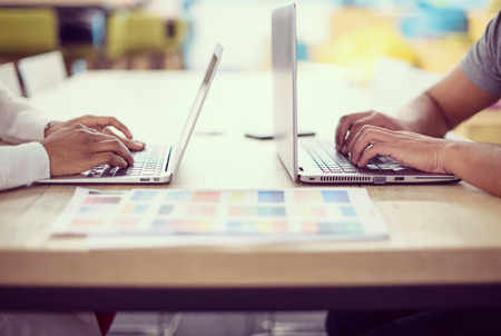 Young successful black muslim business woman having a meeting with her indian male colleague working on the laptop at modern startup officeの写真素材