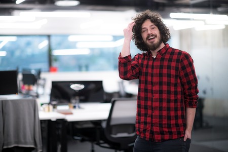 Portrait of young smiling successful male software developer standing at modern startup officeの写真素材