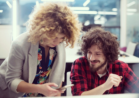 Young software developers couple using laptop and desktop computer while writing programming code at modern creative startup officeの写真素材