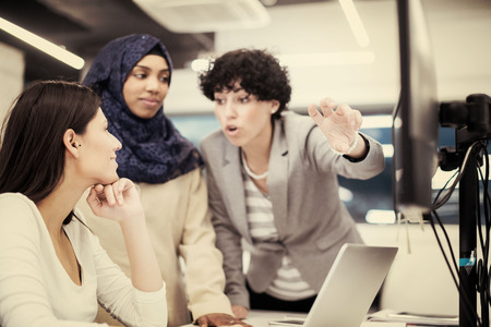 Young multiethnics business team of software developers working together using laptop computer while writing programming code at modern startup officeの写真素材