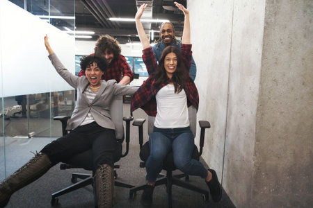 Multiethnics startup business team of software developers having fun while racing on office chairs