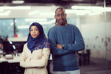 Portrait of black muslim female software developer standing together with her african american male colleague at modern startup officeの写真素材
