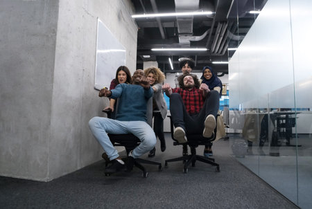 Multiethnics startup business team of software developers having fun while racing on office chairsの写真素材
