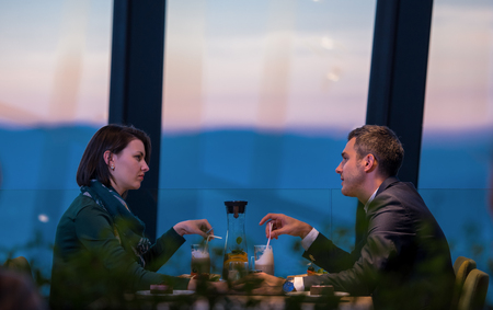 Young happy loving couple enjoying romantic dinner while celebrating Valentines day near the window at luxury restaurantの写真素材
