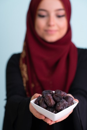 modern muslim woman holding a plate full of sweet dates on iftar time in ramadan kareem islamic healthy food conceptの写真素材