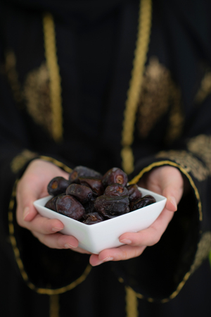 modern muslim woman holding a plate full of sweet dates on iftar time in ramadan kareem islamic healthy food conceptの写真素材