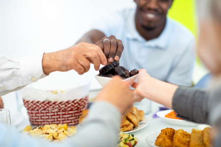 modern multiethnic muslim family sharing a bowl of dates while enjoying iftar dinner together during a ramadan feast at homeの写真素材