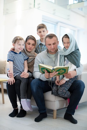 portrait of young happy modern muslim family before iftar dinner during ramadan feast at homeの写真素材