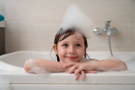 Little girl playing with soap foam in bathの写真素材