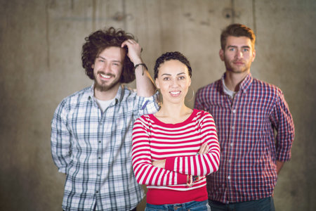 portrait of young successful smiling casual business team standing in front of a concrete wall at...