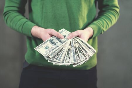 business, people and finances concept  happy young business man displaying a spread of american dollar cash money in new startup officeの写真素材