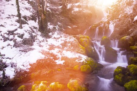 Amazing nature landscape, beautiful waterfall with sunlight in deep winter forestの写真素材