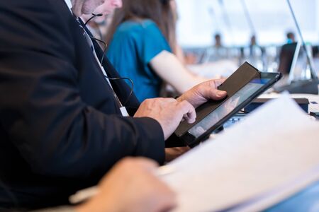 close up shot of business people hands using tablet computer during the business seminar at big modern conference roomの写真素材