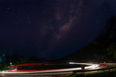 vegicle light trails in night on busy countryroad curve  long exposureの写真素材