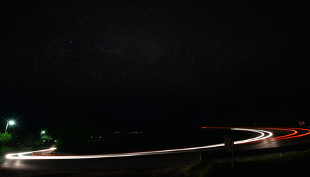 vegicle light trails in night on busy countryroad curve  long exposure