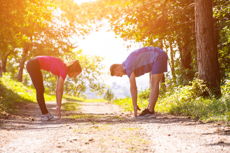 young happy couple enjoying in a healthy lifestyle warming up and stretching before jogging on a...