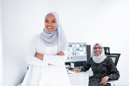 friends at office two young afro american modern muslim business women wearing scarf on creative bright  office workplace with big screenの写真素材