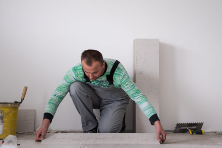 skilled worker installing the ceramic wood effect tiles on the floor Worker making laminate flooring...