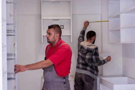 two professional workers installing a new stylish modern kitchen furnitureの写真素材