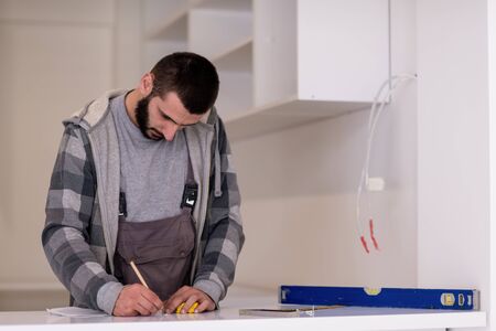 young professional worker writing the measures during installation a new stylish modern kitchen furnitureの写真素材