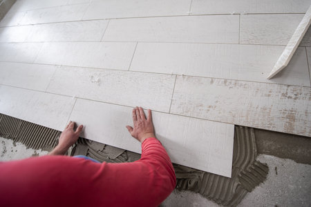 skilled worker installing the ceramic wood effect tiles on the floor Worker making laminate flooring...