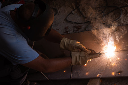 welder with protective mask welding steel structures and bright sparks in construction industry