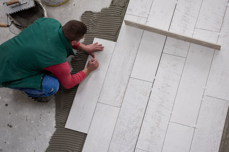 skilled worker installing the ceramic wood effect tiles on the floor Worker making laminate flooring...