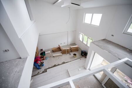skilled worker installing the ceramic wood effect tiles on the floor Worker making laminate flooring on the construction site of the new apartmentの写真素材