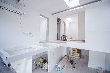 professional carpenter installing new laminated wooden floor in a unfinished apartmentの写真素材
