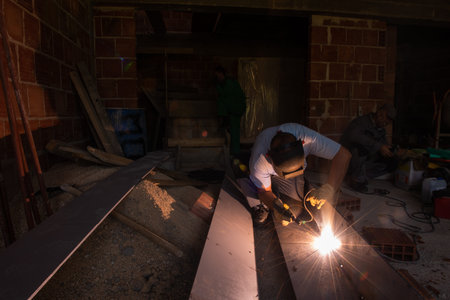 welder with protective mask welding steel structures and bright sparks in construction industry