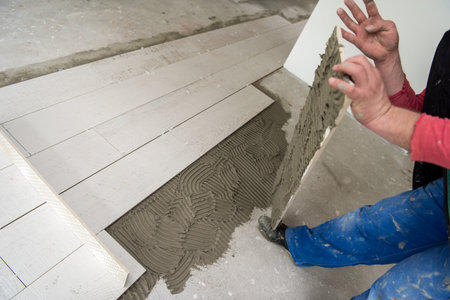 skilled worker installing the ceramic wood effect tiles on the floor Worker making laminate flooring...
