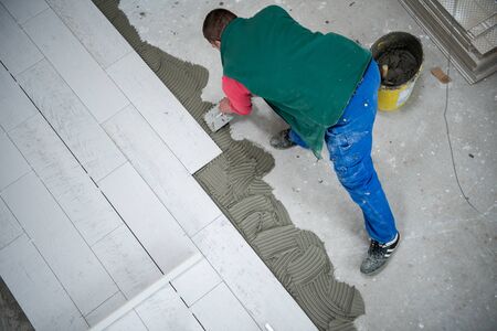 skilled worker installing the ceramic wood effect tiles on the floor Worker making laminate flooring on the construction site of the new apartmentの写真素材