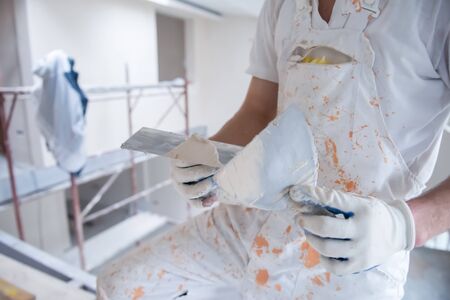 young professional construction worker plastering on gypsum walls inside the new big modern two levels apartmentの写真素材