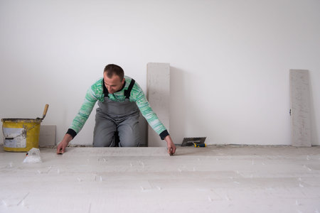 skilled worker installing the ceramic wood effect tiles on the floor Worker making laminate flooring...