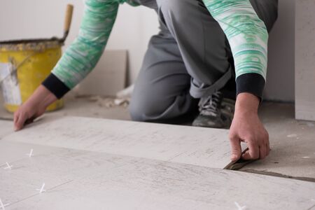 skilled worker installing the ceramic wood effect tiles on the floor Worker making laminate flooring on the construction site of the new apartmentの写真素材