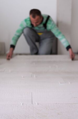 skilled worker installing the ceramic wood effect tiles on the floor Worker making laminate flooring on the construction site of the new apartmentの写真素材