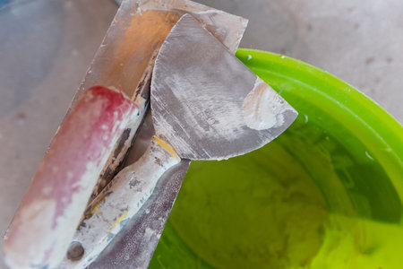 Top view of construction tools in bucket on concrete background. Set of assorted plaster trowel tools and spatulaの写真素材