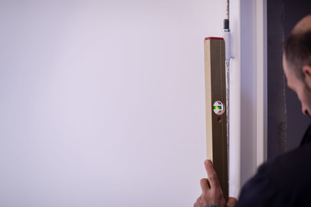male worker carpenters using level tool while installing interior door at new luxury apartment