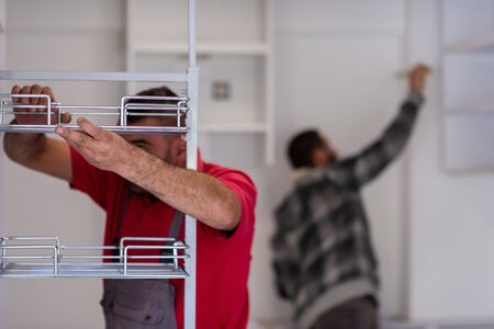 two professional workers installing a new stylish modern kitchen furnitureの写真素材