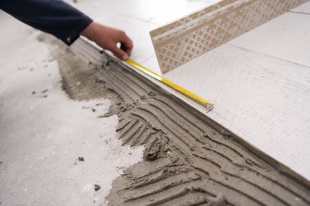 skilled worker installing the ceramic wood effect tiles on the floor Worker making laminate flooring on the construction site of the new apartmentの写真素材