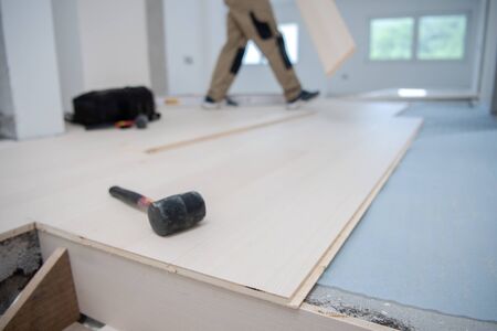 professional carpenter installing new laminated wooden floor in a unfinished apartmentの写真素材