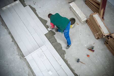 skilled worker installing the ceramic wood effect tiles on the floor Worker making laminate flooring on the construction site of the new apartmentの写真素材