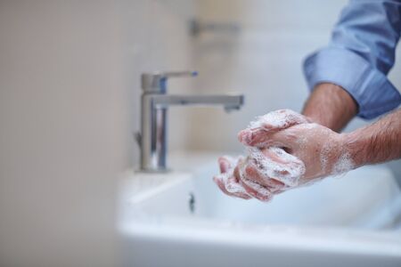 Coronavirus infection and spreading prevention, proper Washing hands with liquid soap. Hygiene male antibacterial hands water wash closeup in bathroom.の写真素材