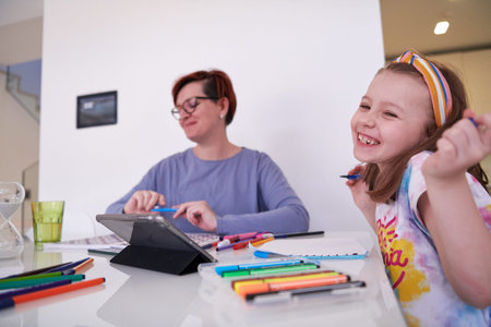 Mother and little daughter  playing together  drawing creative artwork during coronavirus quarantine