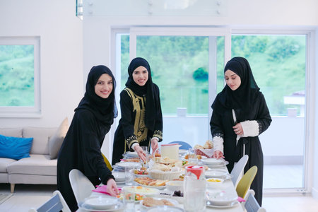 Eid Mubarak Muslim family having Iftar dinner  young muslim girls serving food on the table during...