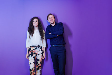 portrait of young happy positive optimistic loving couple posing isolated over purple background