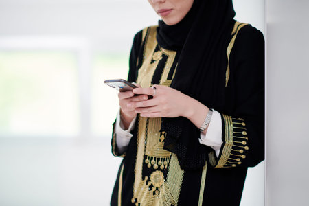 young modern muslim business woman using smartphone wearing traditional hijab clothes at home